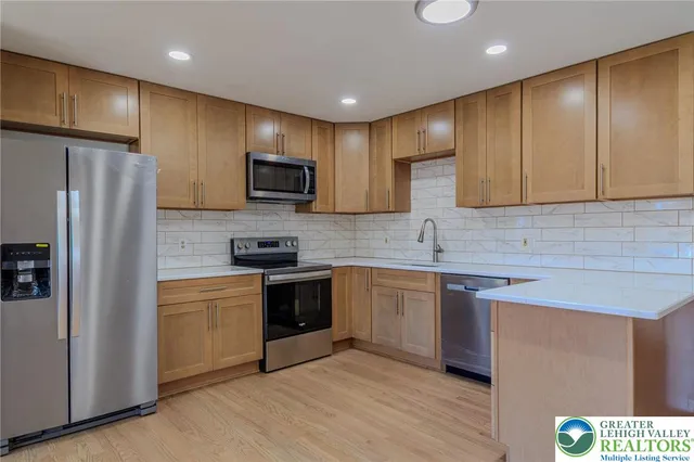 a kitchen with stainless steel appliances granite countertop a stove a sink dishwasher a refrigerator and a microwave oven with wooden floor