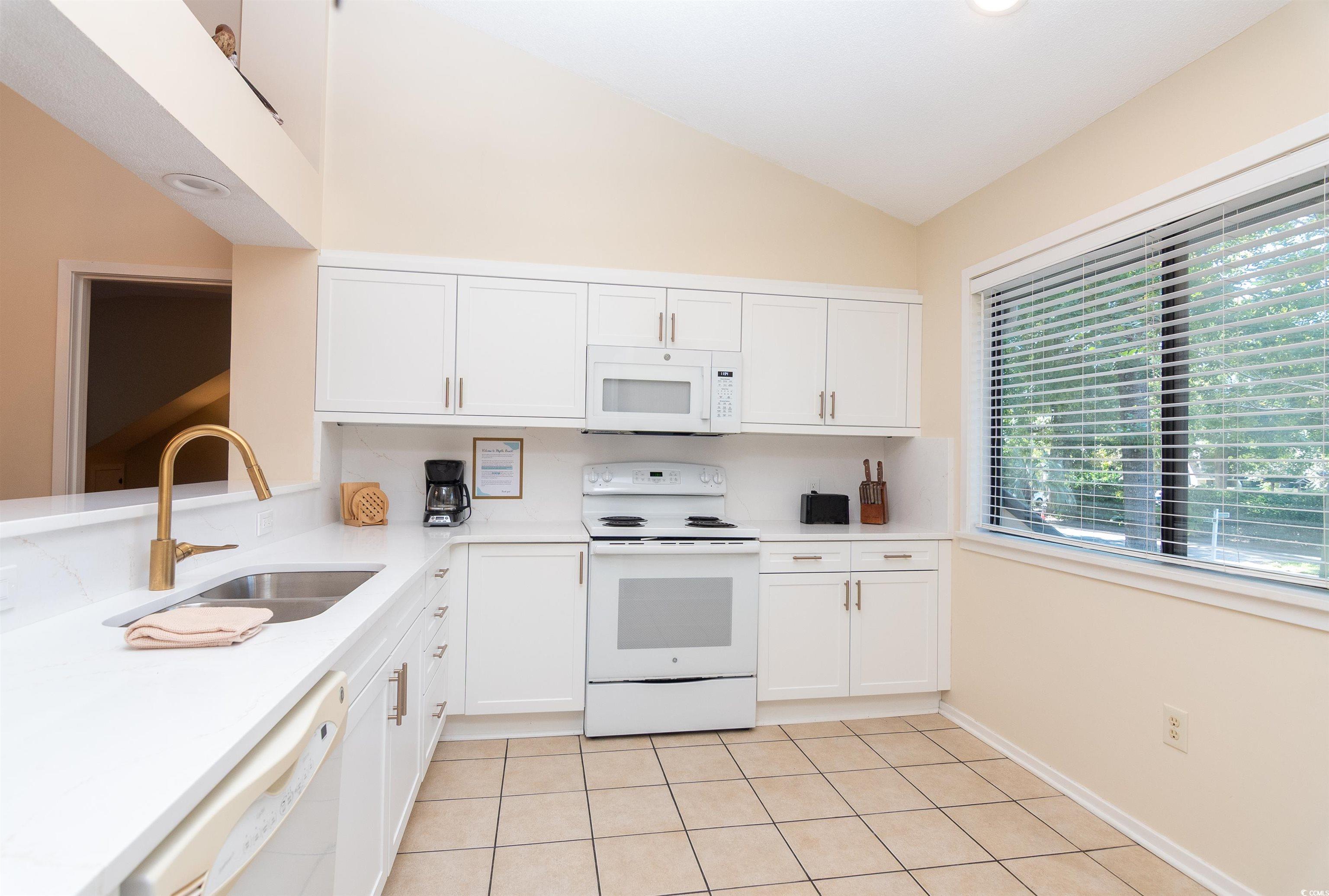 175 St Clears Way, Unit 23I Myrtle Beach, SC 29572 - Photo 11 of 39 Kitchen featuring white cabinets, white appliances, light tile patterned flooring, light stone counters, and vaulted ceiling