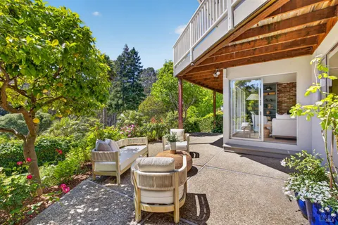 a view of a patio with table and chairs potted plants and floor to ceiling window