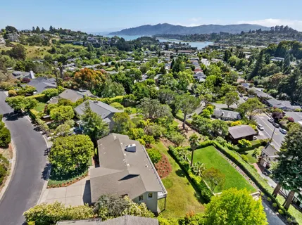 an aerial view of a residential houses with a yard and mountain view in back
