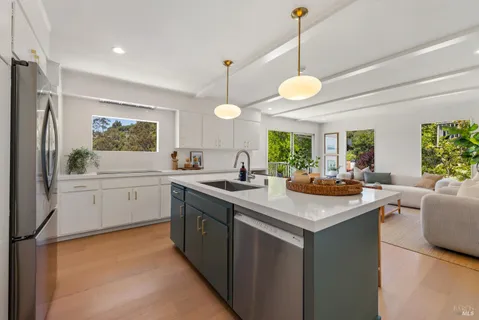 a kitchen with kitchen island granite countertop a stove a sink a refrigerator and a dining table with wooden floor