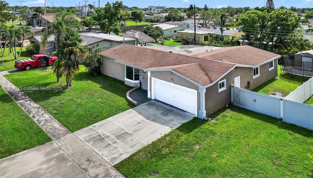 a aerial view of a house in a big yard with plants and large trees