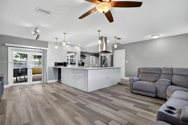 a large white kitchen with cabinets a sink dishwasher a dining table and chairs with wooden floor