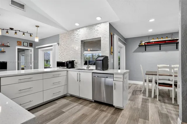a kitchen with cabinets wooden floor and stainless steel appliances