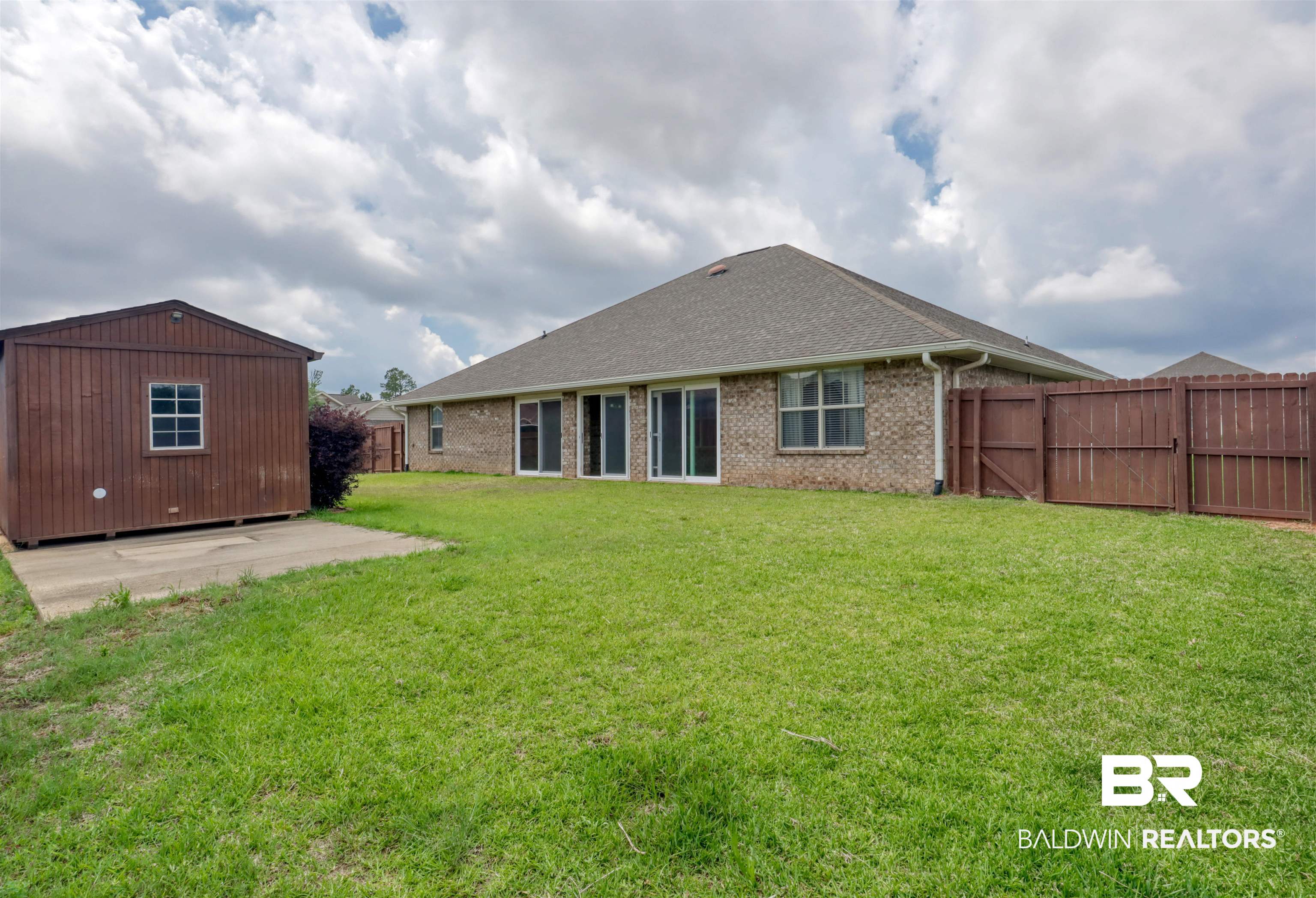 14794 Troon Drive Foley, AL 36535 - Photo 29 of 33 Back of property featuring roof with shingles, brick siding, a fenced backyard, a patio area, and a yard