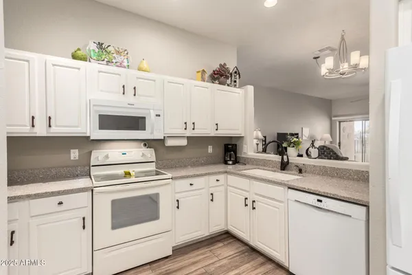 a white kitchen with a sink and dishwasher stove white cabinets with wooden floor