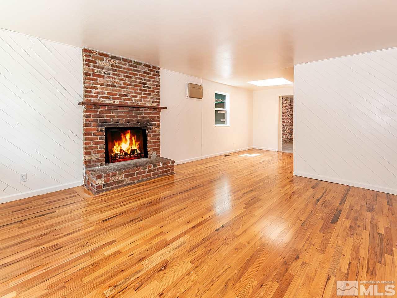 1775 West 6th Street Reno, NV 89503 - Photo 3 of 15 an empty room with wooden floor fire place and windows
