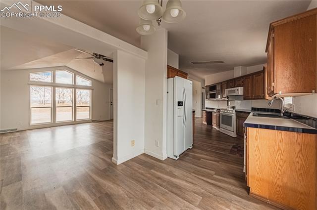 22885 Handle Road Calhan, CO 80808 - Photo 38 of 38 Kitchen featuring white appliances, a ceiling fan, open floor plan, dark wood-style floors, and vaulted ceiling