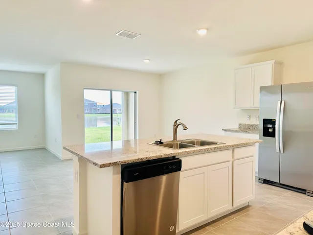 a kitchen with stainless steel appliances granite countertop a sink and a refrigerator