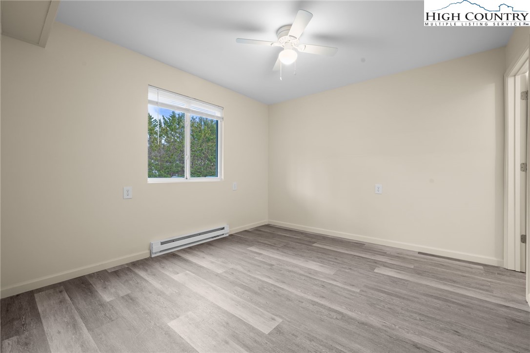128 Zeb Street, Unit A101 Boone, NC 28607 - Photo 13 of 32 an empty room with wooden floor chandelier fan and windows