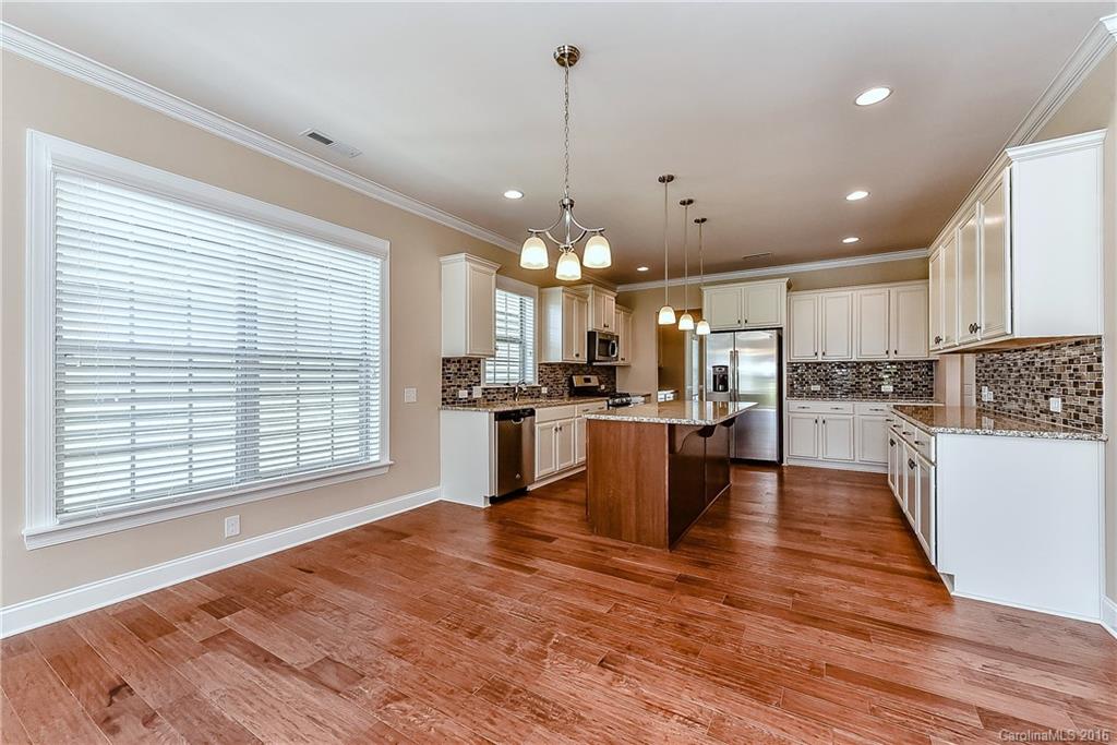 604 Brookhaven Drive, Unit HKC 95 Fort Mill, SC 29708 - Photo 11 of 24 a view of a kitchen with kitchen island a stove a sink a refrigerator wooden floor and a large window