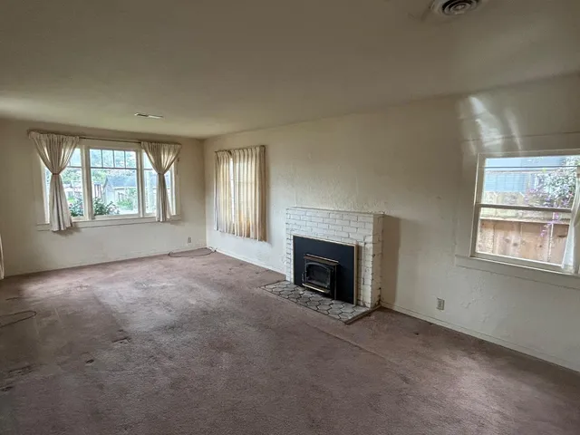 an empty room with windows & fireplace