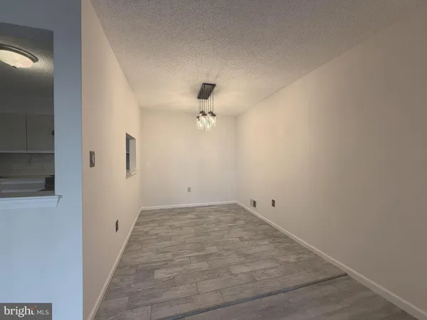 an empty room with chandelier fan and windows