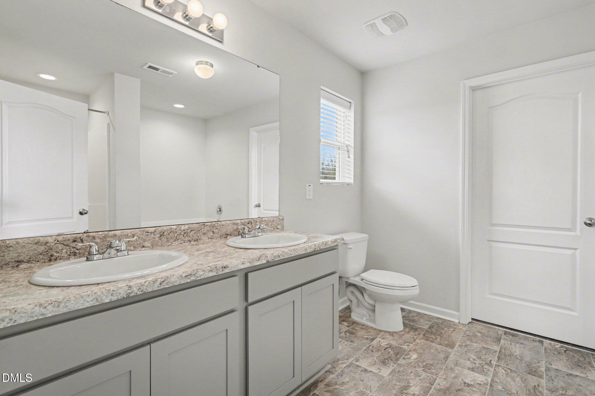 6003 Lowgrass Road Stedman, NC 28391 - Photo 14 of 24 a bathroom with a granite countertop sink a toilet and a mirror