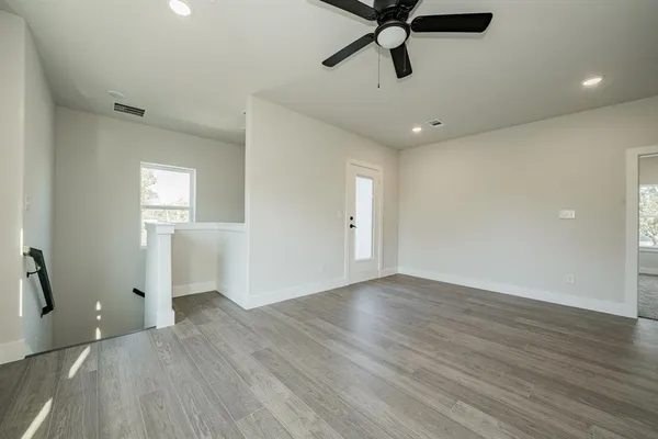 a view of empty room with wooden floor and fan