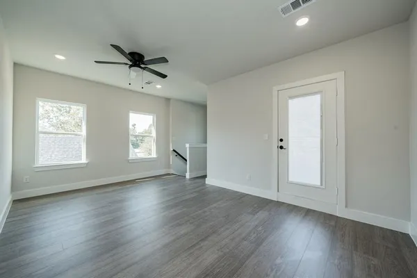 an empty room with windows and a ceiling fan