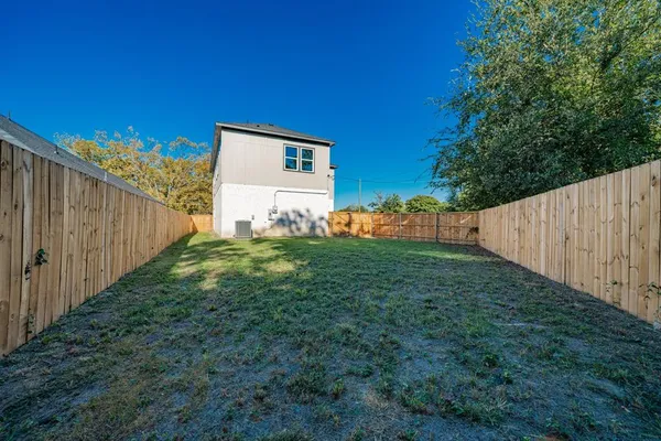 a view of a backyard with large tree and wooden fence