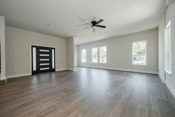 an empty room with wooden floor chandelier and windows