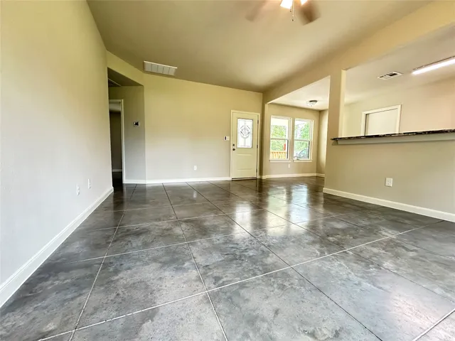 a view of an empty room with window and wooden floor