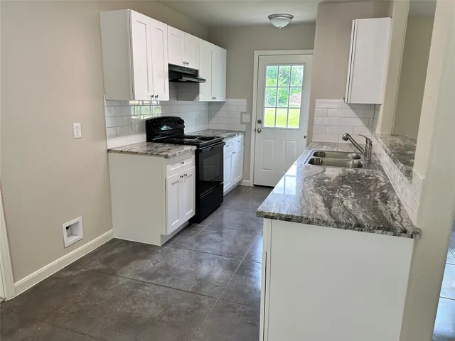 a kitchen with granite countertop white cabinets and window
