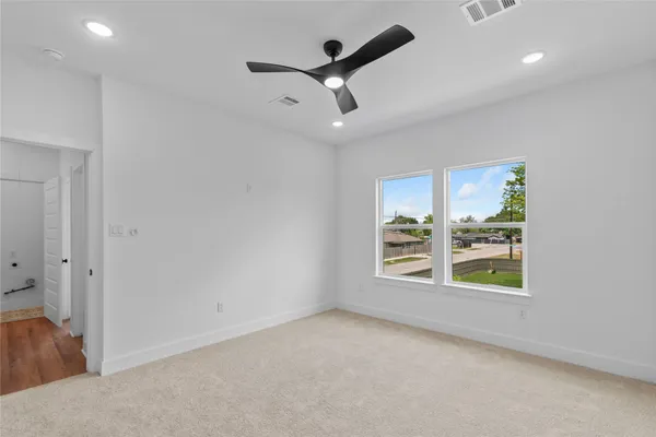 an empty room with a ceiling fan and carpet