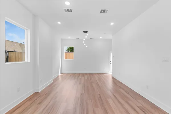a view of an empty room with wooden floor and a window