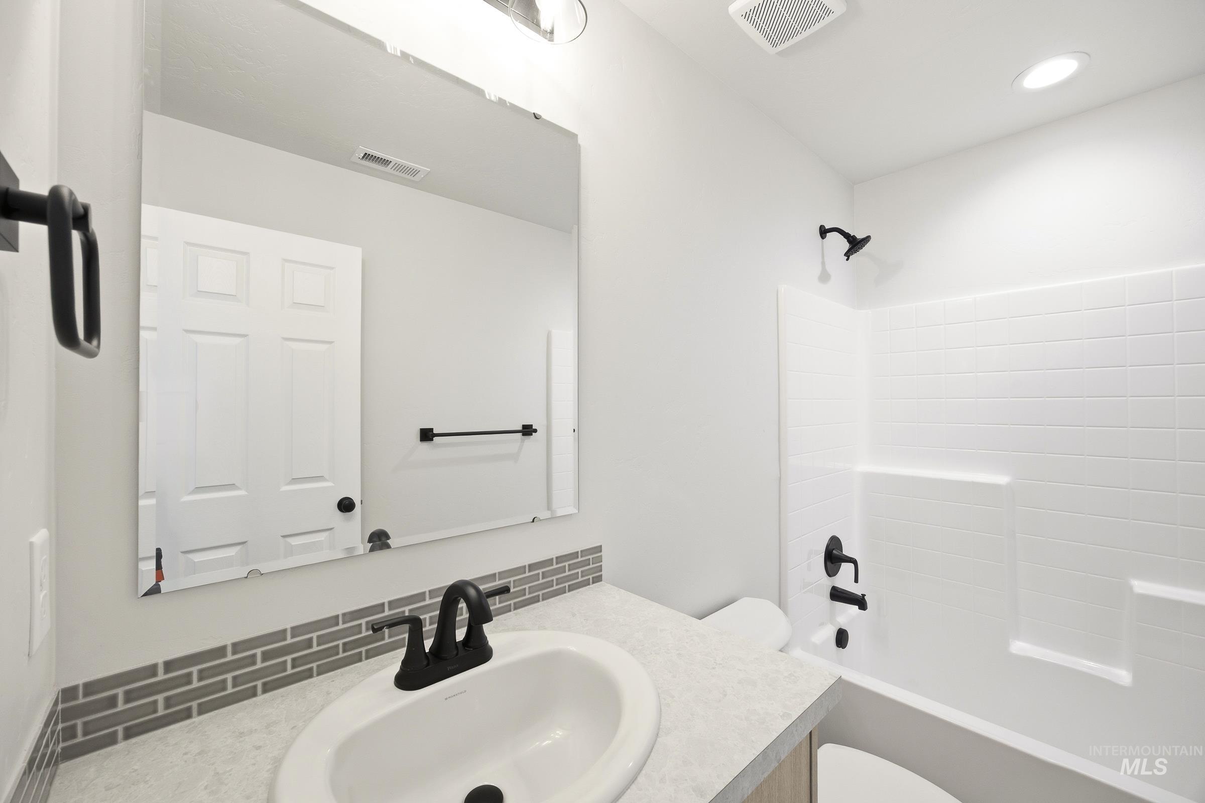 12841 Decatur Street Nampa, ID 83651 - Photo 18 of 30 Bathroom featuring a white integrated sink, dark bronze fixtures, and a subway tile backsplash