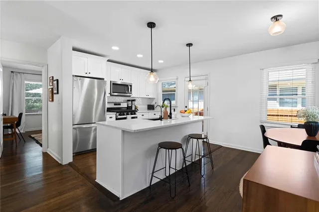 a kitchen with stainless steel appliances granite countertop a refrigerator a oven a sink a stove and white cabinets with wooden floor