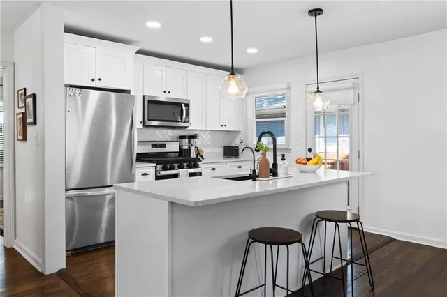 a kitchen with stainless steel appliances a refrigerator a sink a stove a dining table and chairs