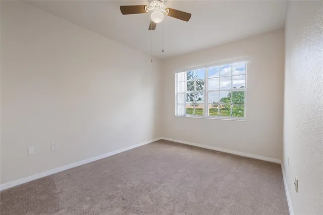 an empty room with windows and ceiling fan
