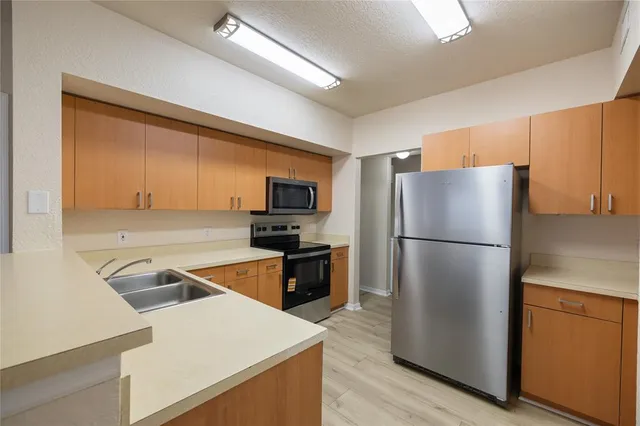 a kitchen with a refrigerator a stove top oven a counter space and wooden floor