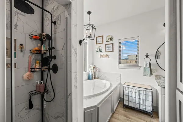 a bathroom with a tub sink a mirror and shower