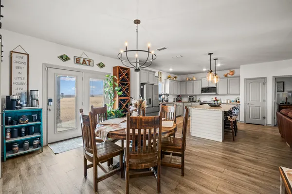 a view of a dining room and livingroom with furniture wooden floor a chandelier