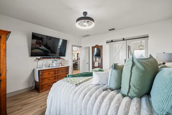 a bedroom with a bed and a flat tv screen on dresser