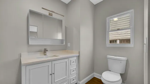 a bathroom with a toilet sink vanity and mirror