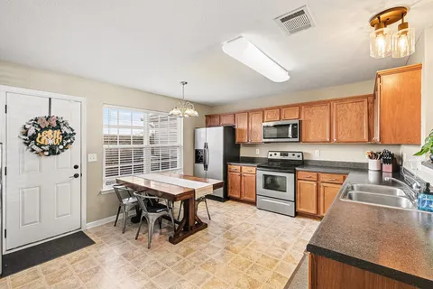 a kitchen with stainless steel appliances kitchen island granite countertop a stove top oven a sink a dining table and chairs