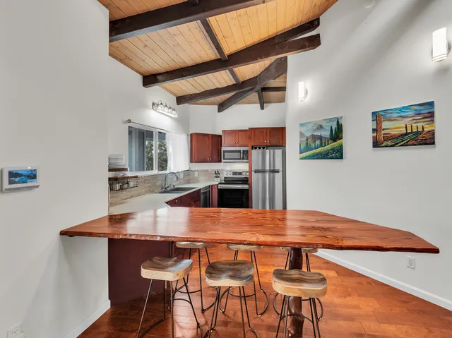 a kitchen with stainless steel appliances wooden floor dining table and chairs