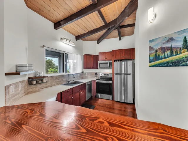 a large kitchen with stainless steel appliances granite countertop a refrigerator a stove and a wooden floors