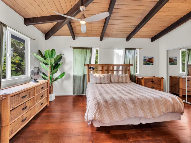 a bedroom with a large bed and wooden floor