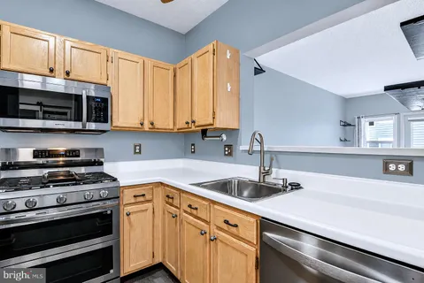 a kitchen with stainless steel appliances granite countertop a sink a stove and cabinets