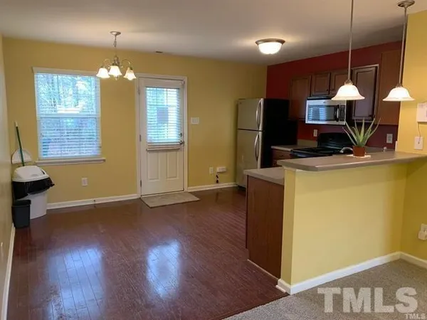 a dining room with wooden floor a chandelier a wooden table and chairs