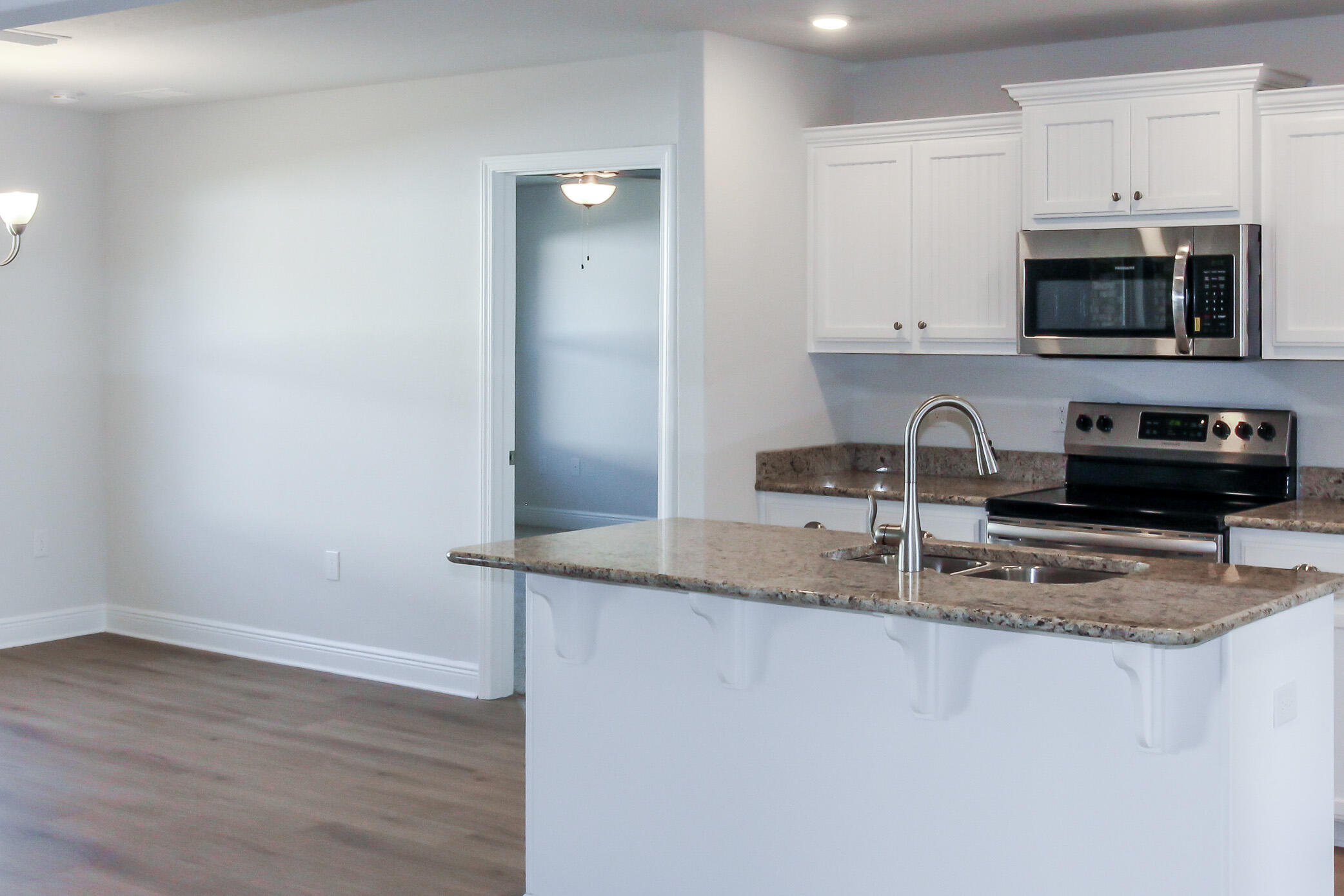 2613 Prominence Lane Crestview, FL 32536 - Photo 8 of 20 a kitchen with stainless steel appliances granite countertop a sink a stove a microwave and wooden cabinets