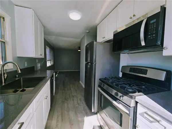 a kitchen with stainless steel appliances granite countertop a sink a stove a microwave and refrigerator