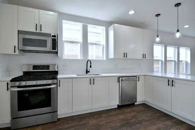 a kitchen with white cabinets appliances and a window