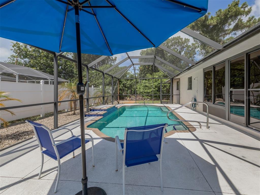1211 Southland Road Venice, FL 34293 - Photo 12 of 80 a view of a backyard with a tub and chairs under an umbrella