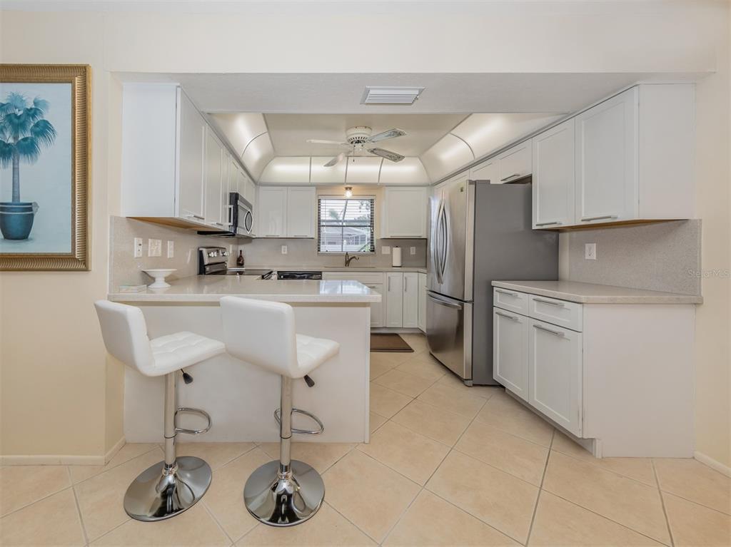 1211 Southland Road Venice, FL 34293 - Photo 18 of 80 a kitchen with stainless steel appliances a sink a stove a refrigerator cabinets and dining table