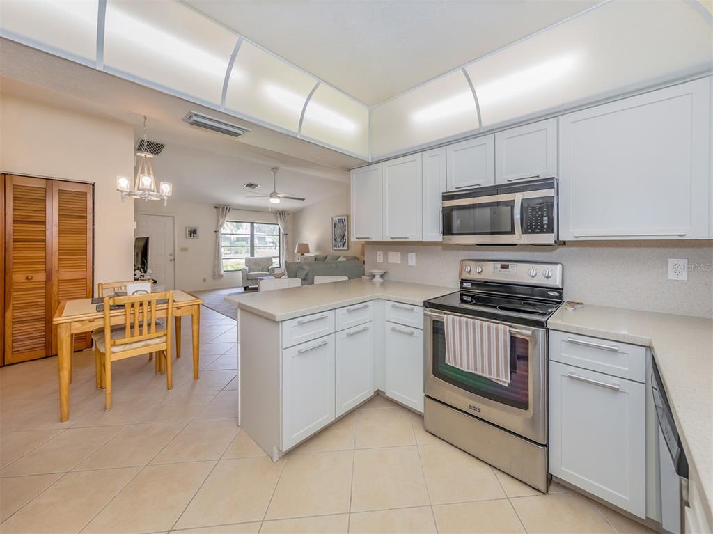 1211 Southland Road Venice, FL 34293 - Photo 22 of 80 a kitchen with stainless steel appliances granite countertop a stove top oven a sink dishwasher a dining table and chairs with wooden floor
