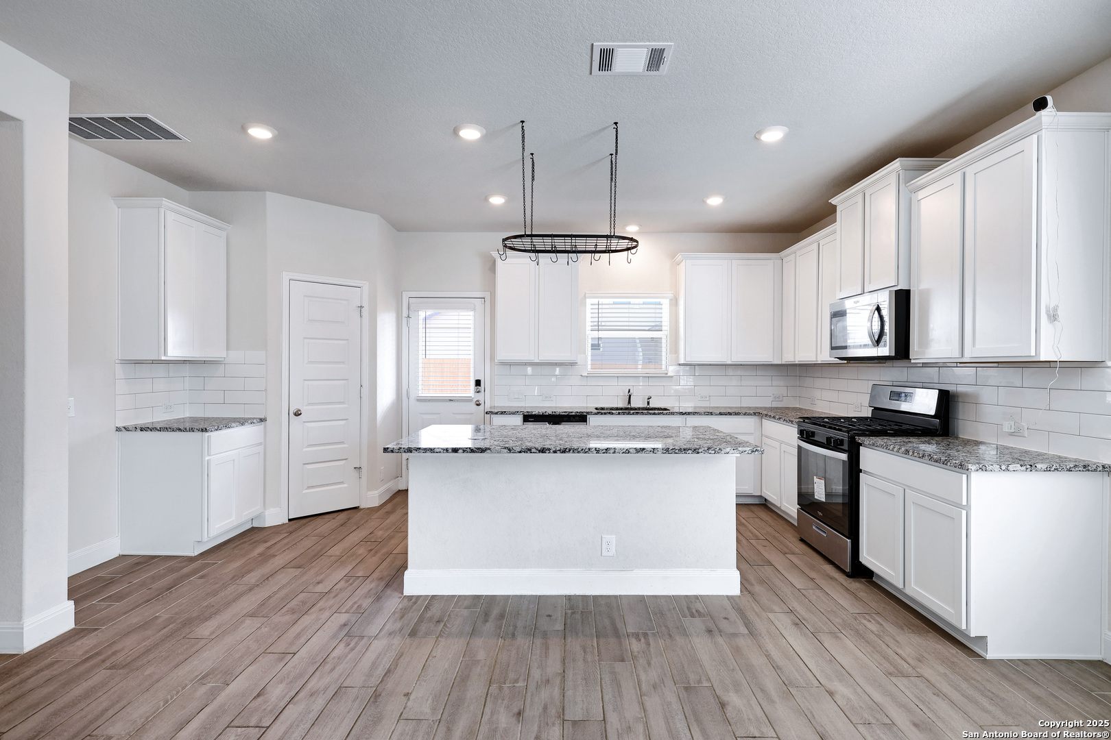 618 Bronze Streme Cibolo, TX 78108 - Photo 9 of 27 a kitchen with kitchen island granite countertop a sink cabinets and wooden floor