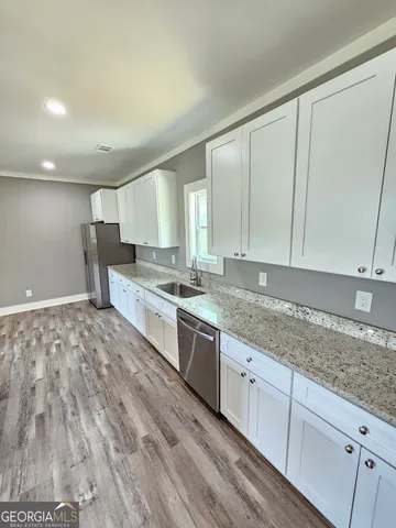 a kitchen with stainless steel appliances granite countertop a wooden cabinets and wooden floor