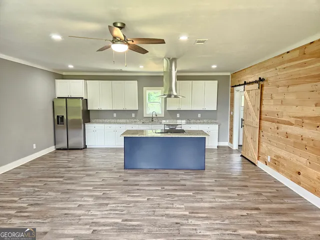 a large kitchen with stainless steel appliances a large counter top a stove a refrigerator and a sink